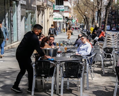 Un camarero limpia una mesa en una terraza en la plaza Manuel Becerra de Madrid, el pasado mayo.