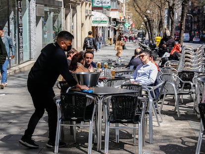 Un camarero recoge una terraza en la plaza Manuel Becerra de Madrid.