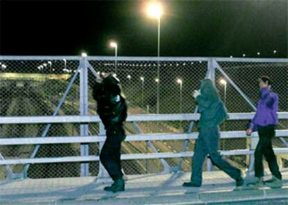 Varios inmigrantes clandestinos cruzan un puente sobre las vías del tren que cruza el canal de la Mancha.