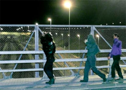 Varios inmigrantes clandestinos cruzan un puente sobre las vías del tren que cruza el canal de la Mancha.