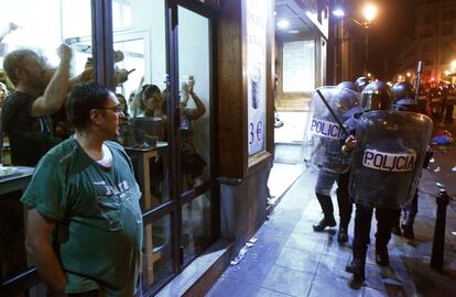 Un grupo de personas en el interior de un bar gritan a la policía antidisturbios que corren detras de los manifestantes, durante la protesta contra las medidas de austeridad anunciadas por el Gobierno, en Madrid.