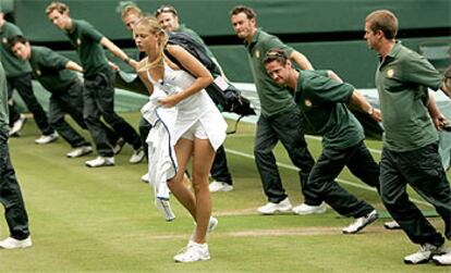 Maria Sharapova se retira mientras que los operarios protegen la pista de la lluvia en una de las interrupciones que sufrió su partido ante Davenport.