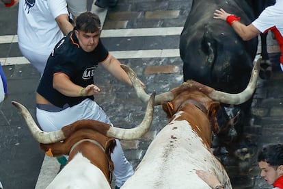 Un corredor trata de zafarse de los astados durante el séptimo encierro de los Sanfermines. 