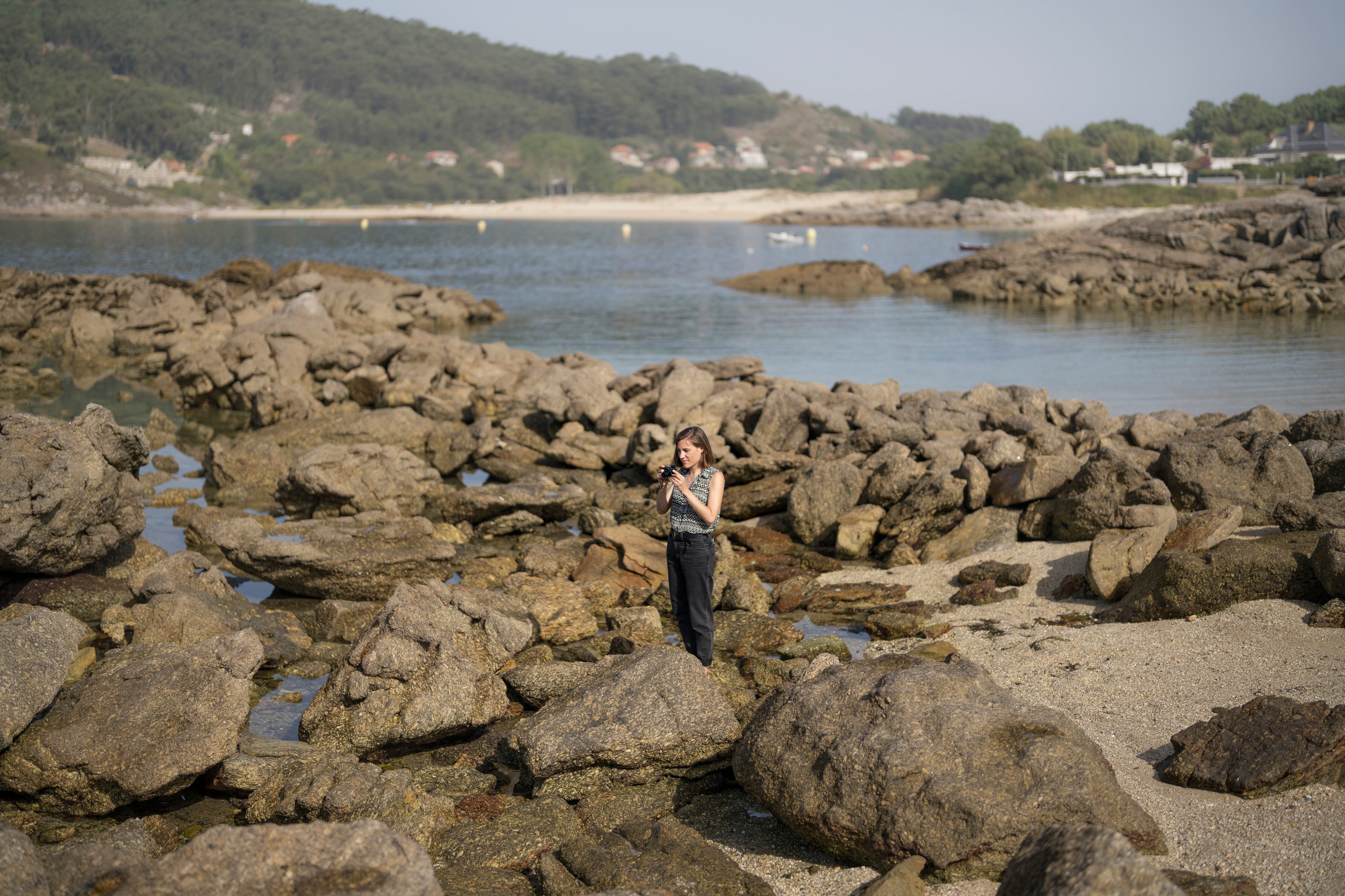 Simón, cámara en mano, localiza entre rocas de la playa de Liméns, cerca de Cangas, Pontevedra.