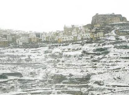 La muela y el núcleo urbano de Ares del Maestre, en el norte de Castellón, cubiertos ayer por la nieve y la niebla.