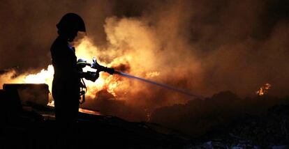 Un bombero extingue el incendio de la escombrera.