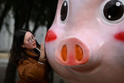 Uma mulher posa com uma escultura em forma de porco, em Pequim, China.