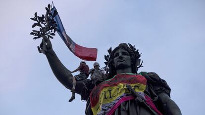 Unos manifestantes contra la extrema derecha colocan banderas, entre ellas la de Francia, en la estatua de la República, en París, el 3 de julio de 2024.