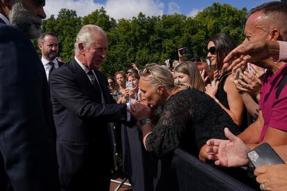 Una mujer besa la mano de Carlos III de Inglaterra a las puertas del palacio de Buckingham Palace, en Londres.