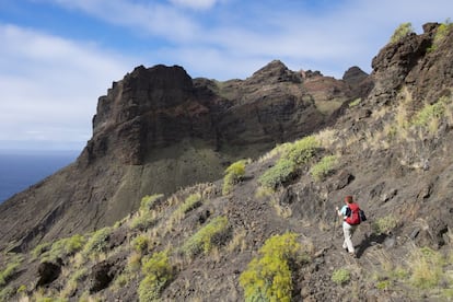 Cuando se habla de las islas Canarias la mayoría de los viajeros piensa en los hoteles y las playas de Tenerife, Lanzarote y Gran Canaria. Pero el archipiélago ofrece innumerables oportunidades para hacer excursiones y descubrir una geografía sorprendente en medio del Atlántico. Una de las mejores discurre por el perímetro de la segunda isla más pequeña, <a href="https://elviajero.elpais.com/tag/la_gomera/a" target="_blank"> La Gomera</a>: es el GR 132, que se puede recorrer en una semana. Siguiendo la costa en la dirección de las agujas del reloj se pasa por terrenos muy diversos con microclimas variados: desde acantilados hasta antiguos bosques nubosos y valles de palmeras, que en muchas ocasiones están cubiertos de bruma. La sensación que produce es la de estar en una isla olvidada por el tiempo (y por los turistas). Cada etapa acaba en un pueblecito —donde se pueden comprar provisiones y sobre todo agua—, y puede que se vean incluso delfines y ballenas. La ruta completa son 122 kilómetros y podemos realizarla de forma circular, con inicio y final en San Sebastián de La Gomera.