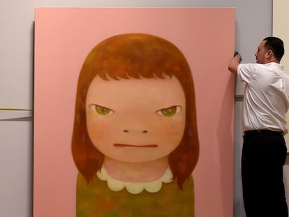 Un trabajador cuelga la obra Yoshitomo Nara  "Wish World Peace", en 2016 en Sothebys New York.