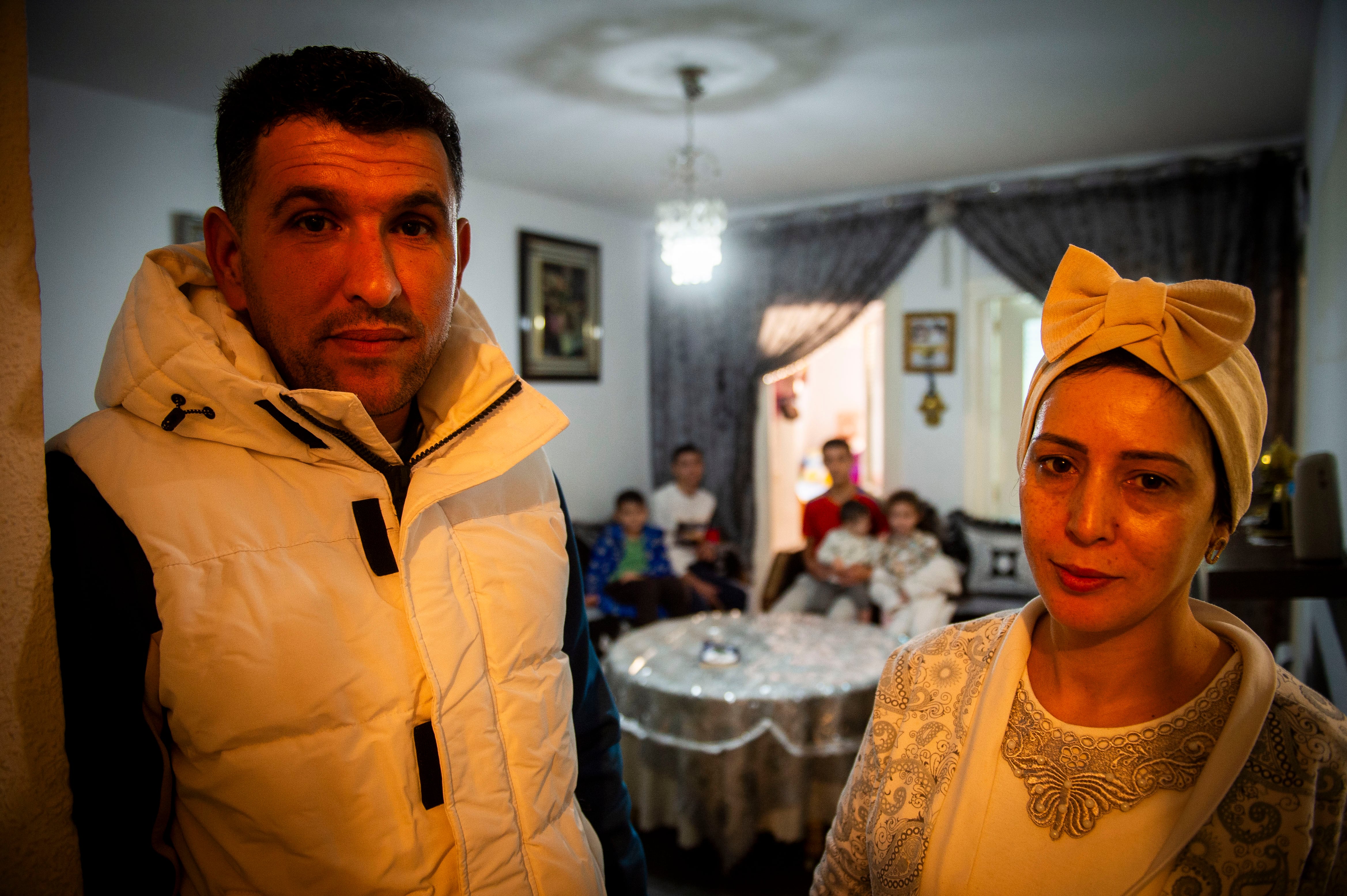 Abdelaziz y Fatima, en primer plano en la puerta de su casa, al fondo, en el salón, sus cinco hijos.  