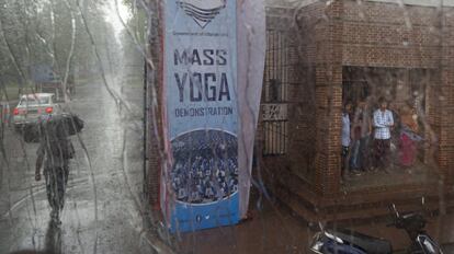 Una fuerza de seguridad privada vigila la puerta del instituto de investigación forestal donde el primer ministro indio, Narendra Modi, celebrará el Día Internacional de Yoga. Mientras, los locales se refugian de una repentina lluvia en Dehradun, India.