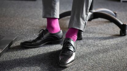 Hombre trajeado con unos calcetines en color rosa.