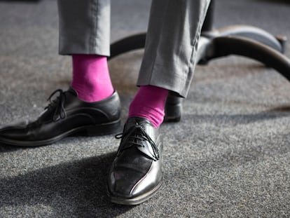 Hombre trajeado con unos calcetines en color rosa.