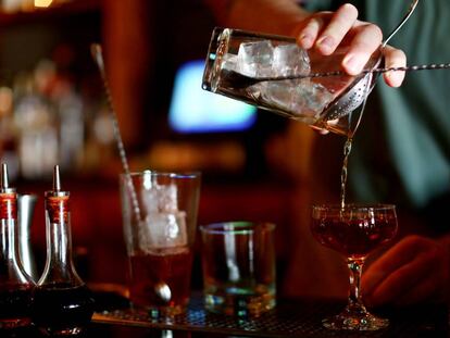 Un barman mezcla un cóctel con whisky en un bar.