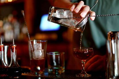 Un barman mezcla un cóctel con whisky en un bar.