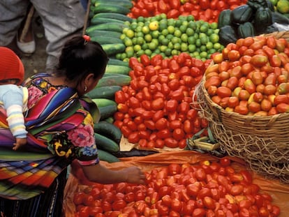 Una mujer compra verdura en un mercado en Guatemala.