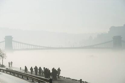 Un grupo de peatones camina entre la niebla por la orilla del río Danubio en Budapest (Hungría).