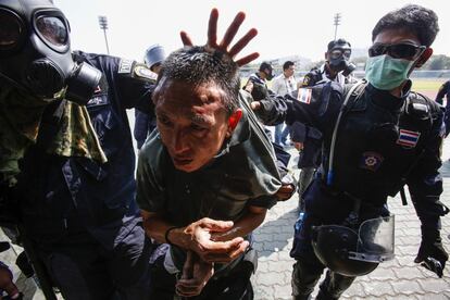 Policías antidisturbios detienen a un manifestante contra el gobierno durante los enfrentamientos en los alrededores del estadio del centro de Bangkok.