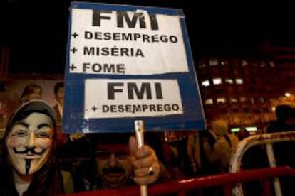 Un manifestante sostiene un cartel en el que se lee "FMI: desempleo, hambre, miseria" durante una protesta contra la entidad Fondo Monetario Internacional (FMI) cerca a la delegación de esa entidad en Lisboa, Portugal. EFE/Archivo