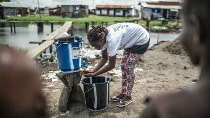 Una voluntaria muestra a los vecinos de Clara Town medidas higiénicas para evitar el contagio.