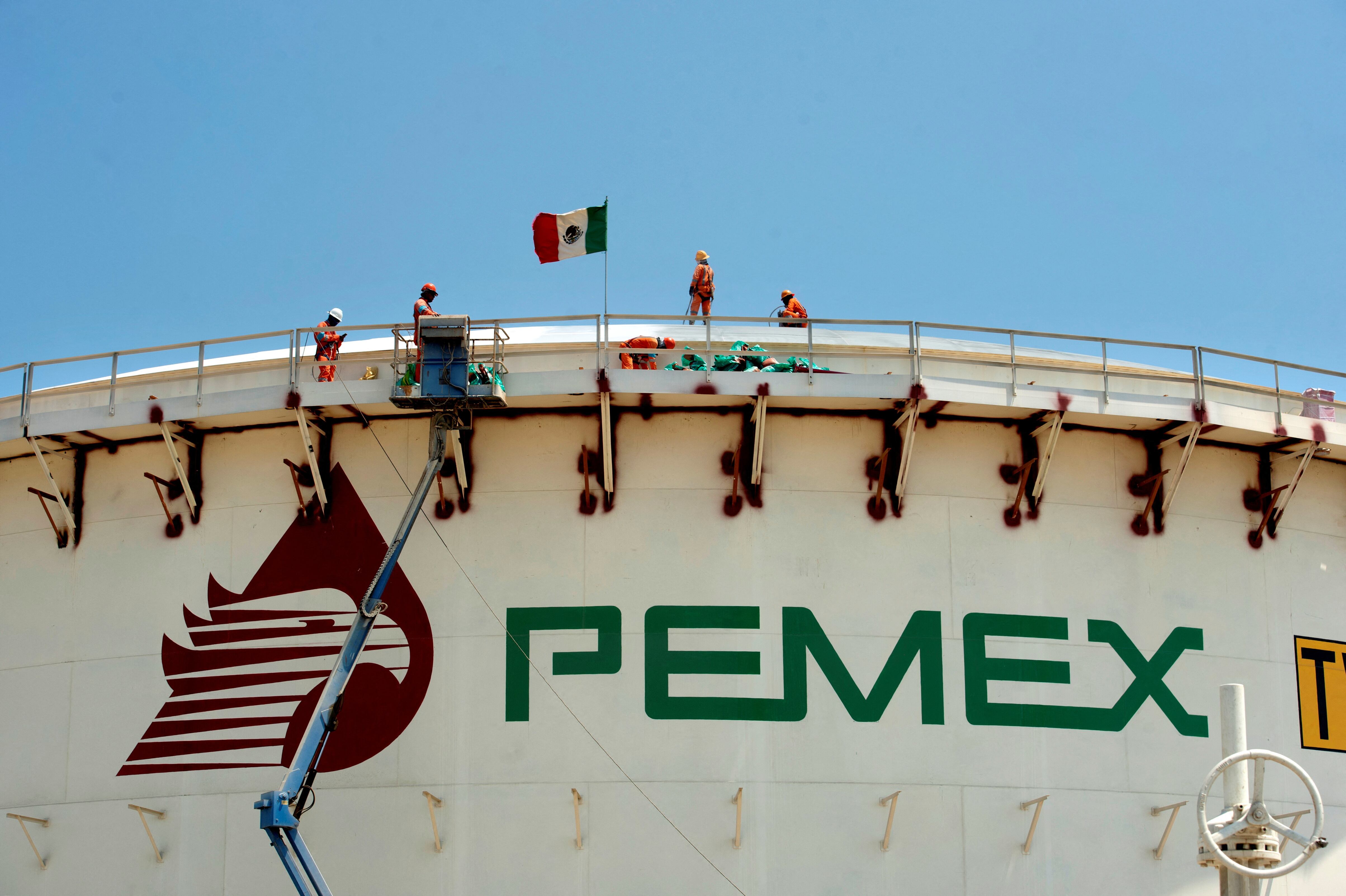 Trabajadores encima de un tanque, durante la construcción de la refinería.