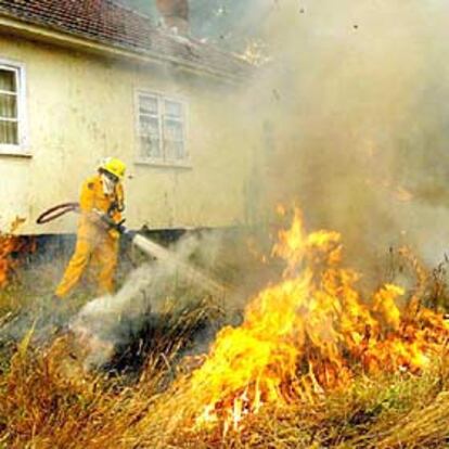 Un bombero sofoca las llamas que acechan una casa cerca de Sydney.