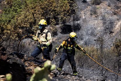 Dos bomberos sofocan la zona calcinada en Colera, este sábado.