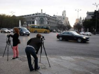 Aficionados a la fotografía sacan imágenes del Banco de España, en la madrileña Plaza de Cibeles. EFE/Archivo