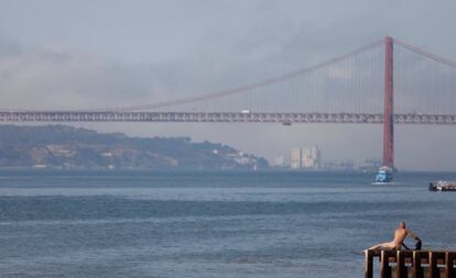 Un hombre se seca al sol después de nadar en el río Tajo en Lisboa (Portugal).