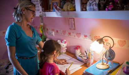 Una nena fa els deures amb l'ajuda de la seva mare.