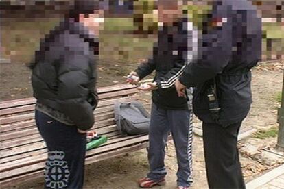Dos agentes de policía registran hoy a dos menores, en las cercanías de un instituto de enseñanza media en Madrid.