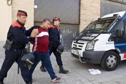Dos <i>mossos </i>conducen a uno de los detenidos de la banda de robo de cobre, ayer en Barcelona.
