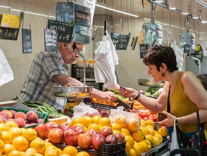Una mujer paga su compra en una frutería de Barcelona.