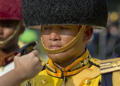 Un trabajador de primeros auxilios rocía agua sobre un soldado que viste con el atuendo ceremonial a la espera del discurso público del Rey Maha Vajiralongkorn de Tailandia, tras su coronación, en Bangkok.