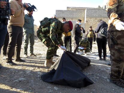 Un soldado con restos de asesinados por el ISIS hallados en Irak el martes.