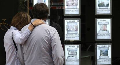 Una pareja observa anuncios de pisos en una inmobiliaria en Madrid.