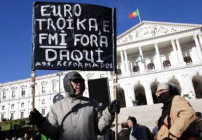 Un pensionista sostiene una pancarta en la que se puede leer "Euro y troika fuera de Portugal" durante una jornada de protestas organizada por el sindicato CGTP en contra de la subida de impuestos para los Presupuestos del Estado de 2014, delante del edificio del Parlamento, en Lisboa (Portugal). EFE/Archivo