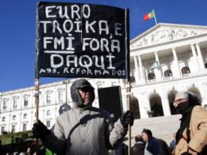 Un pensionista sostiene una pancarta en la que se puede leer "Euro y troika fuera de Portugal" durante una jornada de protestas organizada por el sindicato CGTP en contra de la subida de impuestos para los Presupuestos del Estado de 2014, delante del edificio del Parlamento, en Lisboa (Portugal). EFE/Archivo