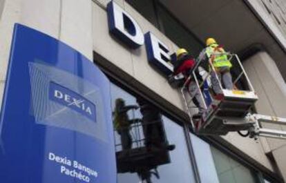 Los trabajadores retiran el logo del banco Dexia de la sede de la entidad en Bruselas, Bélgica. EFE/Archivo