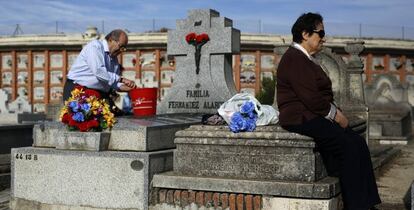 Un hombre limpia una tumba en el cementerio de La Almudena de Madrid.