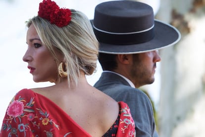 Una mujer vestida de flamenca observa el Real sobre la grupa del caballo durante la Feria de Abril de Sevilla. 