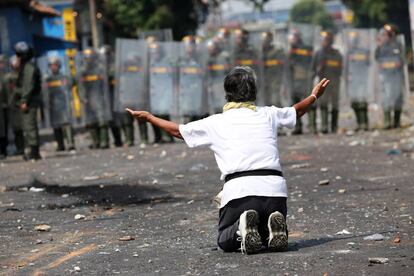 Un manifestante se arrodilla ante miembros de la Guardia Nacional, en Ureña