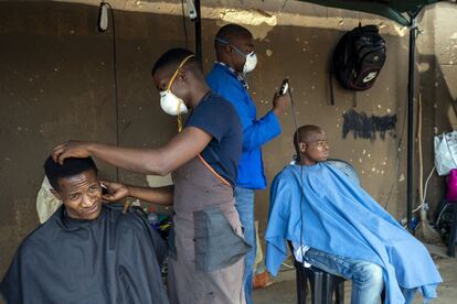 Sudáfrica. La peluquería y barbería a pie de calle es un servicio habitual en muchos países africanos. Estos barberos con máscaras protectoras atienden a sus clientes en Soweto, en las afueras de Johanesburgo, el miércoles 25 de marzo de 2020. Con el aislamiento impuesto ya no se puede realizar.