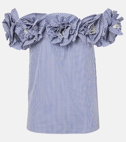 Carolina Herrera declina aquí una de sus prendas más características: la camisa clásica. En esta ocasión la convierte en una pieza primaveral y femenina gracias a su escote Bardot que deja los hombros al descubierto y a las flores de telas que lo recorren. (1.340 euros).