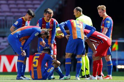 El arbitro Mateu Lahoz y varios jugadores se interesan por el estado del jugador del Barcelona Sergio Busquets, conmocionado tras un golpe.