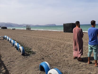 Los hermanos Usama y Mohamed, en una playa de la bahía de Alhucemas desde donde partió su hermano menor, Marwan, hacia España. Al fondo se encuentra el peñón de Alhucemas, con una base militar española.