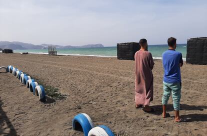 Los hermanos Usama y Mohamed, en una playa de la bahía de Alhucemas desde donde partió su hermano menor, Marwan, hacia España. Al fondo se encuentra el peñón de Alhucemas, con una base militar española.
