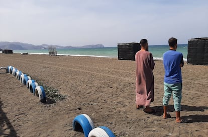 Los hermanos Usama y Mohamed, en una playa de la bahía de Alhucemas desde donde partió su hermano menor, Marwan, hacia España. Al fondo se encuentra el peñón de Alhucemas, con una base militar española.